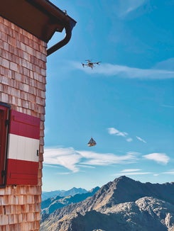 Rispetto ai voli in elicottero, i voli con droni non producono emissioni dirette di CO₂ e comportano costi sensibilmente inferiori. Inoltre, consentono forniture più flessibili e frequenti in piccole quantità. (Foto: Flyingbasket.com)