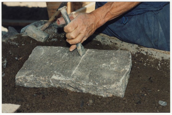 Mit Hammer und Meißel wird der Porphyr „formatiert“, sprich, zu einer Platte mit einer quadratischen Grundfläche gespalten: Die Arbeit wird auch heute noch vielfach in reiner Handarbeit durchgeführt. (Foto: Bruno Canali)