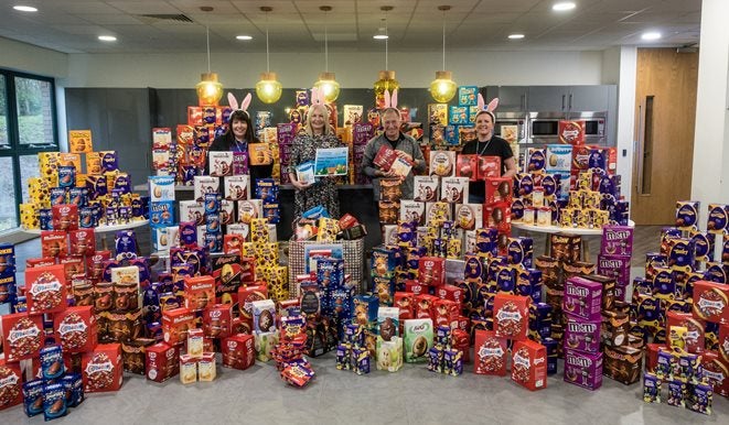 Four people with a large collection of donated Easter eggs and chocolates.