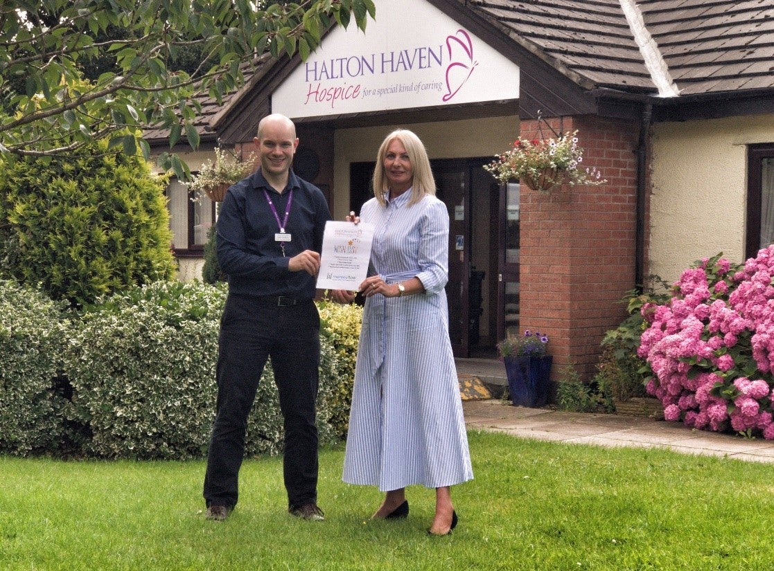 Two people holding a certificate outside Halton Haven Hospice
