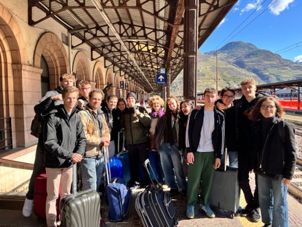 Gruppo di studenti della Scuola Alberghiera Cesare Ritz di Merano alla stazione, pronti per partire per un'esperienza di mobilità Erasmus+, occasione unica di crescita e formazione internazionale.