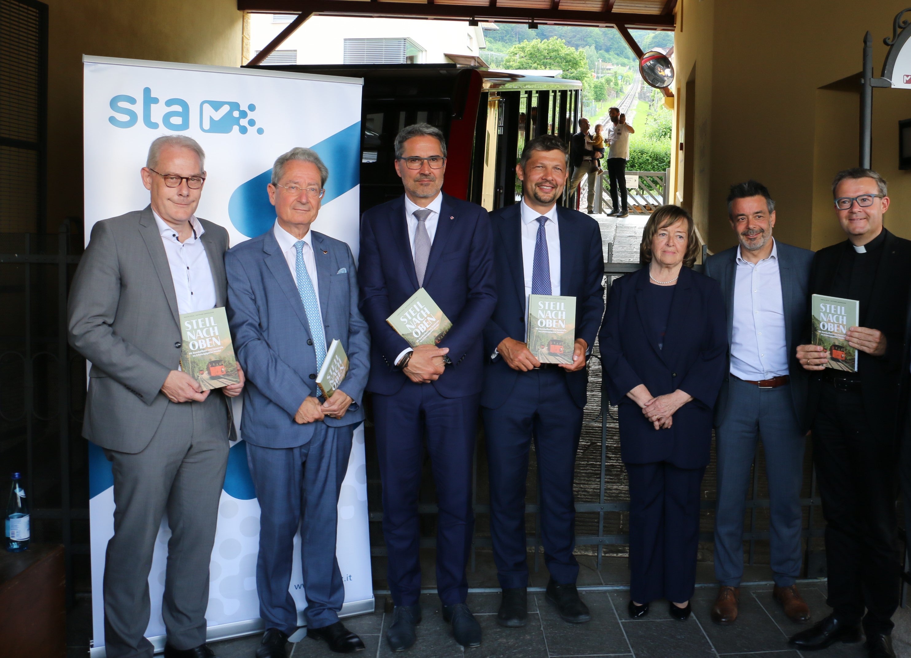 Alla cerimonia per il 120° anniversario della funicolare: l'assessore comunale Hermann Atz, il cittadino onorario di Caldaro Alexander von Egen, il presidente della Provincia autonoma di Bolzano Arno Kompatscher, l'assessore provinciale alla Mobilità Daniel Alfreider, il sindaco Gertrud Benin Bernard, il direttore della Sta Joachim Dejaco e il decano Alexander Raich (Foto: ASP/Ingo Dejaco)