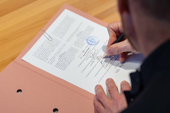 L presidënt dla Jonta provinziela de Bulsan Arno Kompatscher, a man ciancia, y i ambolc, a man drëta, sotscrij la cunvenzion. (Foto: USP/Greta Stuefer)