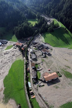 Archivbild: Der Blick auf den Großbergbach und den Weiler Fußendraß am Tag nach der Überschwemmung, am 5. August 2012, zeigt das Ausmaß der Schäden. Im Hintergrund hinter der Baumgruppe erkennbar die Rückhaltesperre, die erst knapp ein Jahr vor dem Unwetterereignis errichtet worden war. (Foto: LPA/Landeswarnzentrum in der Agentur für Bevölkerungsschutz)