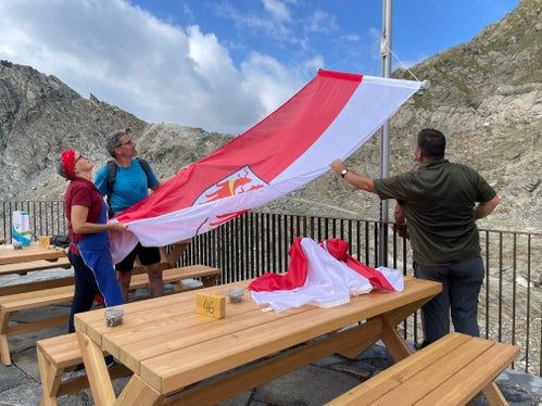 Il presidente  Kompatscher mentre issa la bandiera della Provincia insieme ai gestori del rifugio Petrarca (Foto: ASP/G.News)
