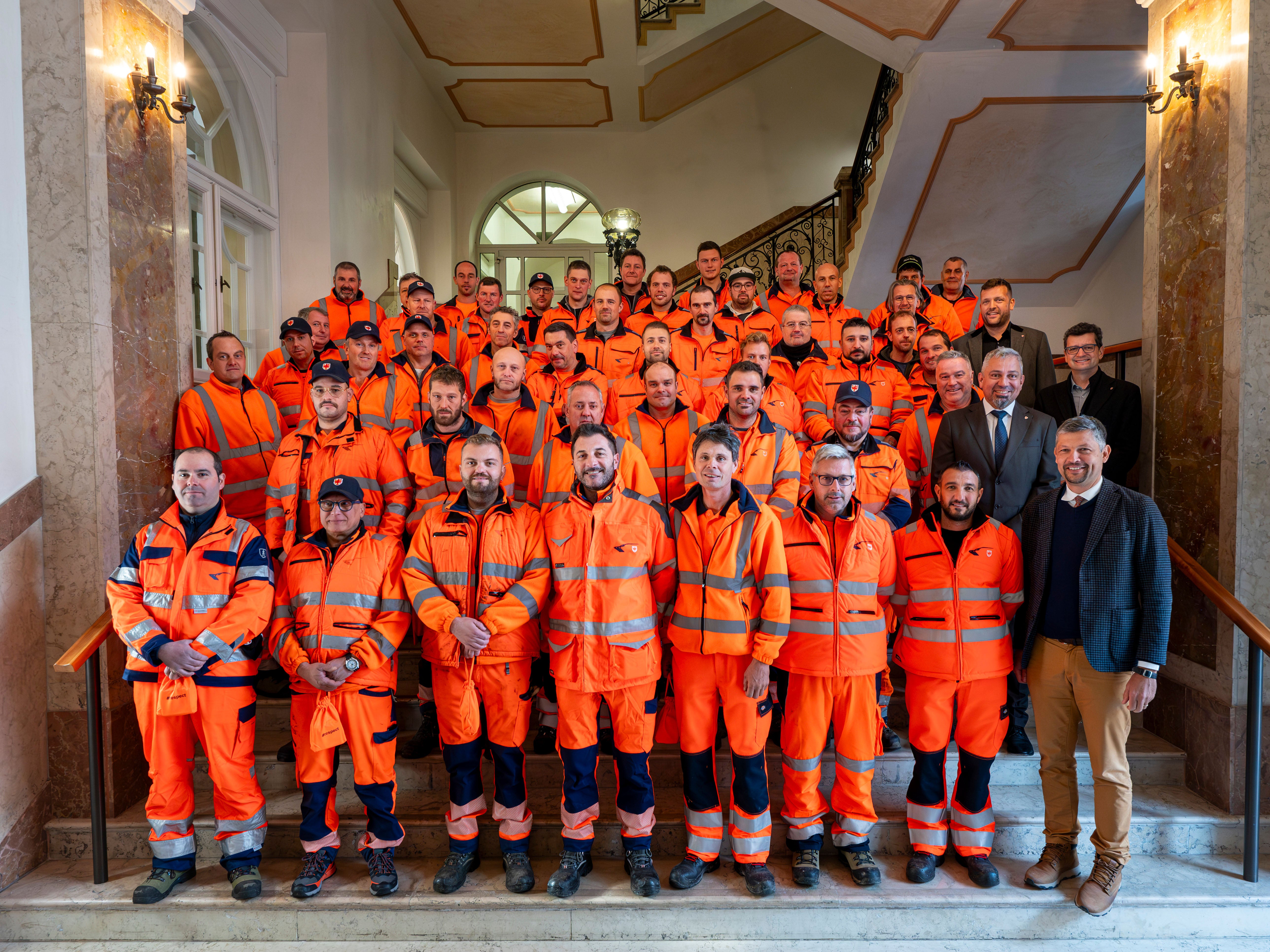 Mobilitätslandesrat Daniel Alfreider (vorne rechts), Generaldirektor Alexander Steiner (2. Reihe rechts), Abteilungsdirektor Philipp Sicher (4. Reihe rechts) und Amtsdirektor Günter Sölva (3. Reihe rechts) begrüßten bei der Feier fast 60 neue Straßenwärter des Landes im Palais Widmann in Bozen. (LPA/Fabio Brucculeri)