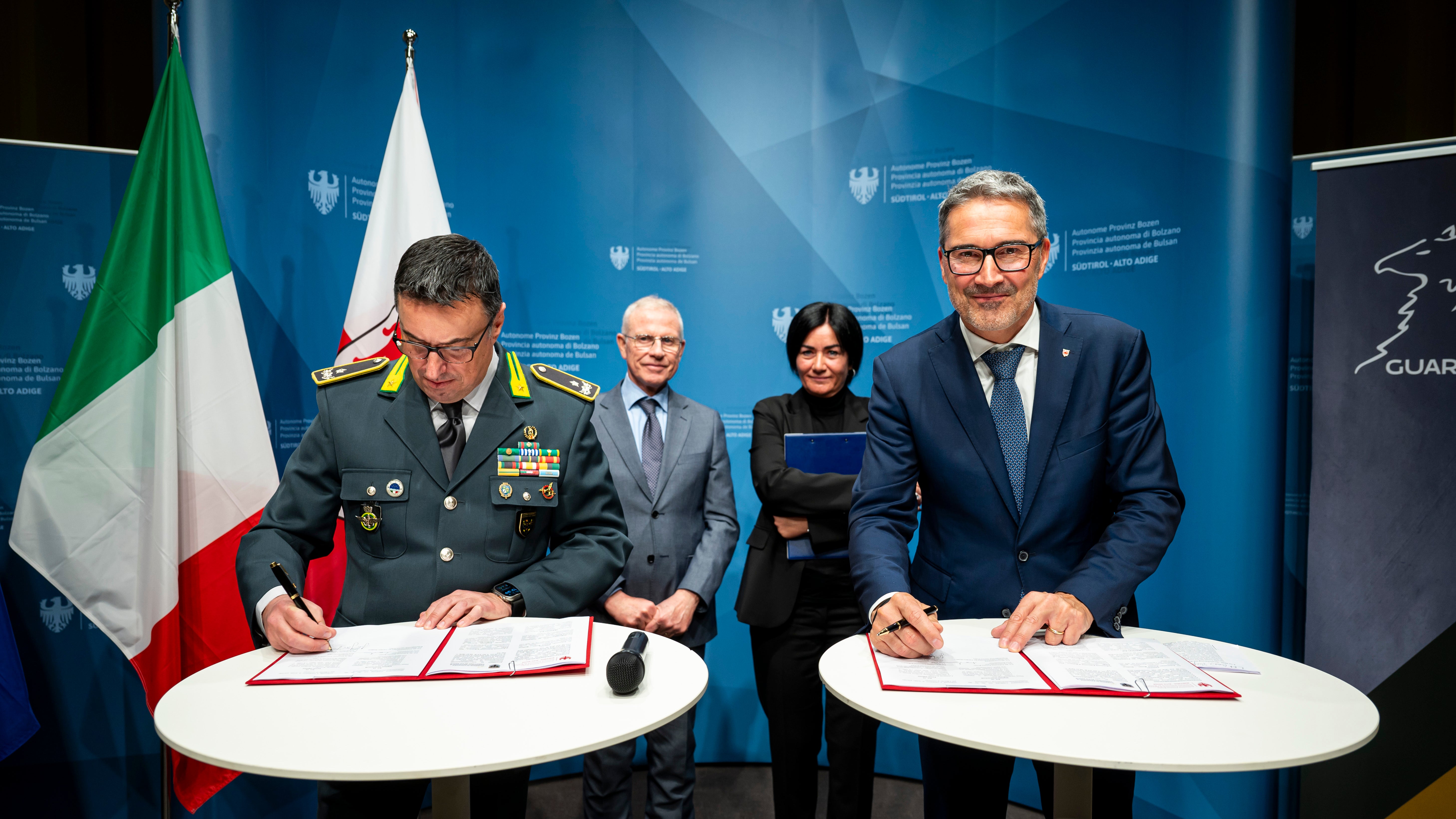 Der regionale Kommandant der Finanzwache für Trentino-Südtirol, General Gavino Putzu (links) und Landeshauptmann Arno Kompatscher (rechts) unterzeichneten vor Regierungskommissar, Präfekt Vito Cusumano und Landesrätin Ulli Mair (im Hintergrund) die Vereinbarung zur Organisation von Wettbewerbsverfahren für Personal mit Zweisprachigkeitsnachweis. (Foto: LPA/Fabio Brucculeri)