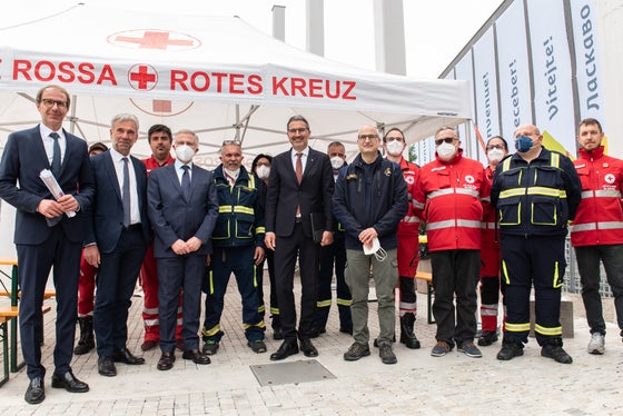 Davanti al centro di accoglienza (da sinistra): il direttore della protezione civile Unterweger, l'assessore Schuler, il commissario del governo Cusumano, il presidente della Provincia Kompatscher, il capo della protezione civile Curcio con i rappresentanti della Croce Bianca e della Croce Rossa (Foto: ASP/Ivo Corrà)