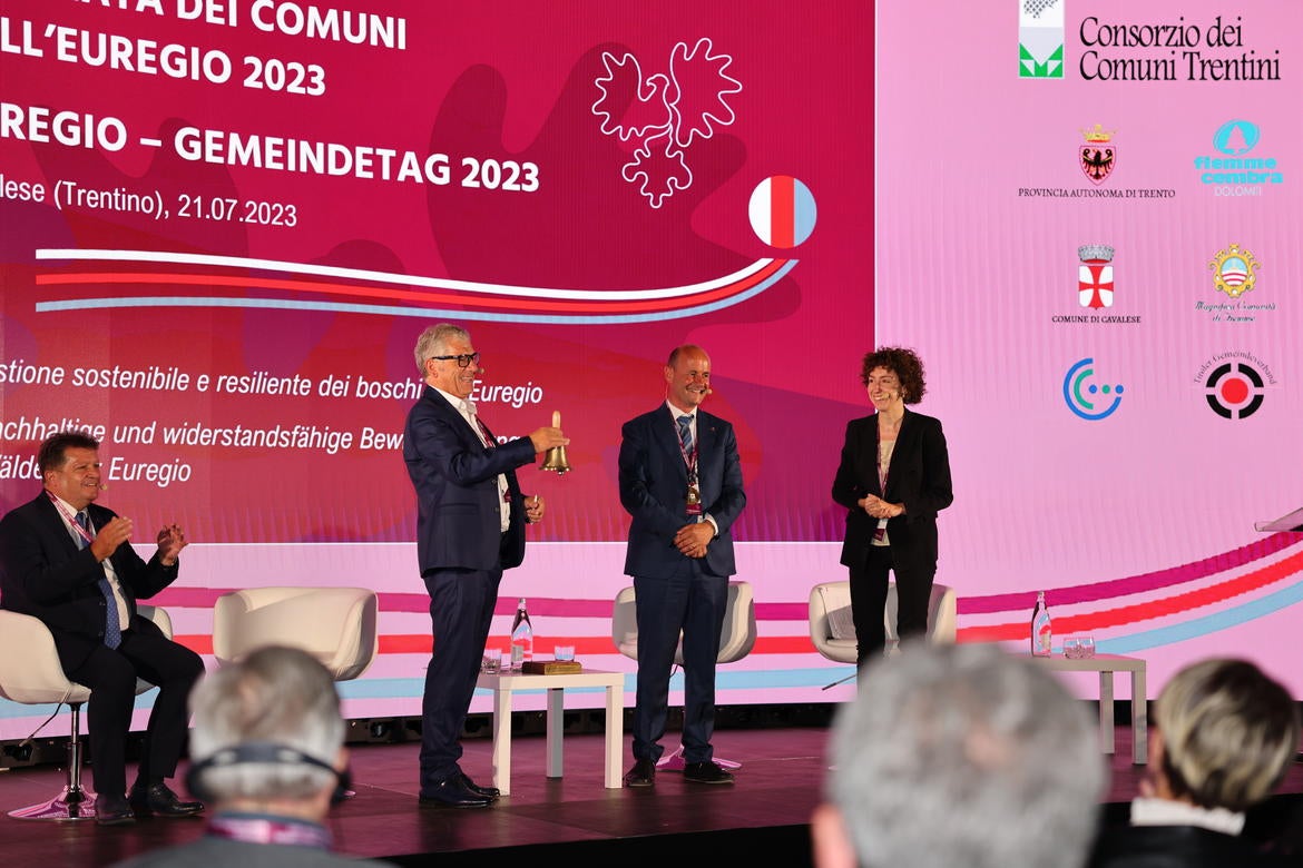 Die Übergabe der Glocke und damit des Vorsitzes des Euregio-Rates der Gemeinden von Paride Gianmoena (Trentino) an Südtirols Gemeindenpräsident Andreas Schatzer. (Foto: Presseamt Trentino/Juliet Astafan)