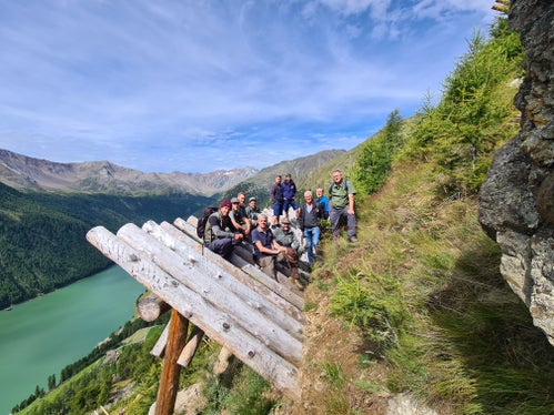 Foto di gruppo sulle strutture in legno di protezione dalle valanghe: gli operatori dell'Ufficio sistemazione bacini montani Ovest con i colleghi dell'Ispettorato forestale di Merano durante una visita al sistema di protezione delle valanghe Hochegg a Vernago in Val Senales (Foto: ASP/Ispettorato forestale di Merano)