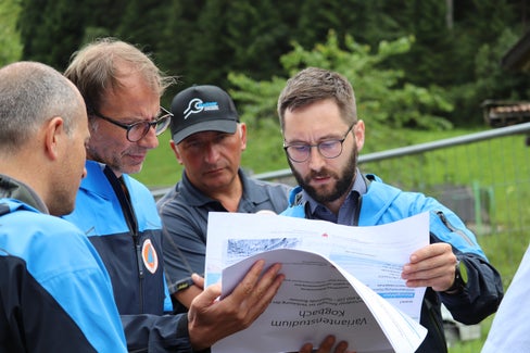 Vor Beginn der Arbeiten am Toffringbach (mit den Plänen der Arbeiten am Kogbach) am 13. Juli dieses Jahres (v.l.): Amtsdirektor Philipp Walder, Bevölkerungsschutz-Agenturdirektor Klaus Unterweger, Vorarbeiter Roland Langgartner, Projektant und Bauleiter Jan Kobald (Foto: LPA/Maja Clara)