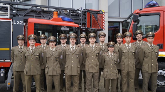 Die Absolventen und die Absolventin des elften Ausbildungskurs zum Feuerwehrmann beziehungsweise zur Feuerwehrfrau mit soeben erhaltenem Brustabzeichen mit dem Wappen der Berufsfeuerwehr; dieses ist in der Uniformordnung an der Jacke der Sonntagsuniform vorgesehen und somit Teil der Uniform und ein Merkmal, an der ein Berufsfeuerwehrmann oder eine Berufsfeuerwehrfrau zu erkennen ist. (Foto: LPA/Berufsfeuerwehr)