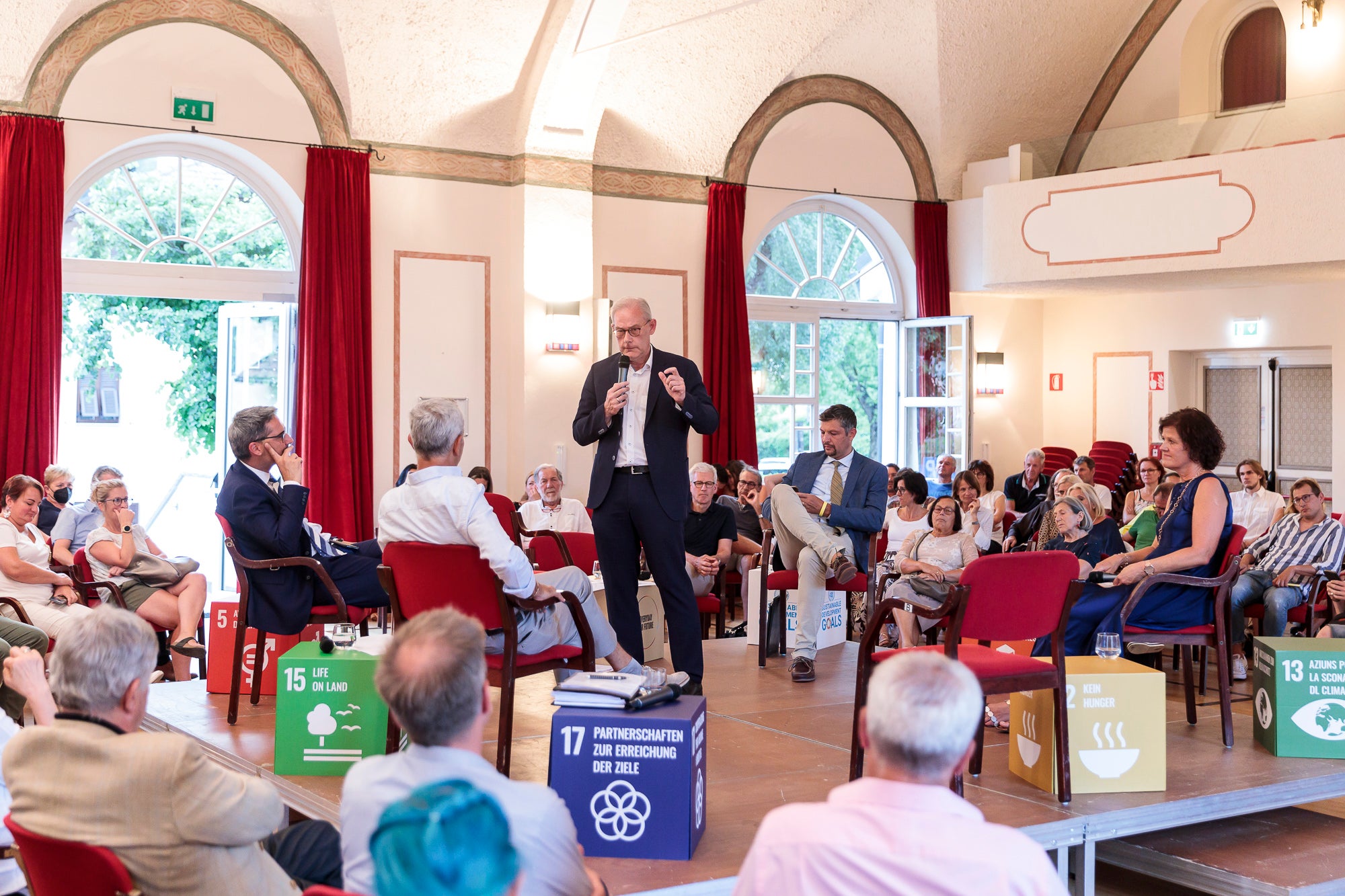 Stellten eingangs ihre Ziele und Erfahrungen vor: (am Podium v.l.) LH Kompatscher, Nachhaltigkeitsbeauftragter Zublasing (Gemeinde Eppan), Vizebürgermeister und Nachhaltigkeitsbeauftragter Atz (stehend, Gemeinde Kaltern), LR Alreider und Moderatorin Karin Tanzer. (Foto: LPA/Tiberio Sorvillo)