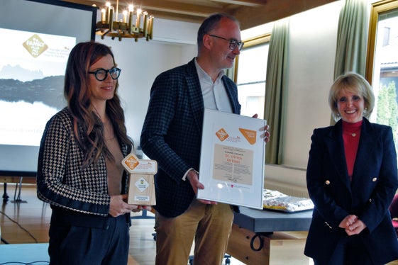 L’assessëura per la familia Waltraud Deeg (r.) ti à sëurandat al ambolt Tobia Moroder (tamez) y ala referënta de chemun Martina Comploi (l.) la uneranza cun chëla che l chemun de Urtijëi vën premià coche chemun a mesura dla families. (Foto: LPA/Greta Stuefer)