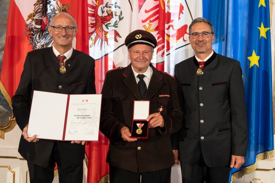Con il suo impegno pluriennale nei pompieri, è un rappresentante delle personalità meritevoli di rappresentare uno dei corpi più rinomati sul territorio: Anton Schraffl di S. Giorgio di Brunico con i governatori Mattle (a sinistra) e Kompatscher (a destra). (Foto: Land Tirolo/Die Fotografen)