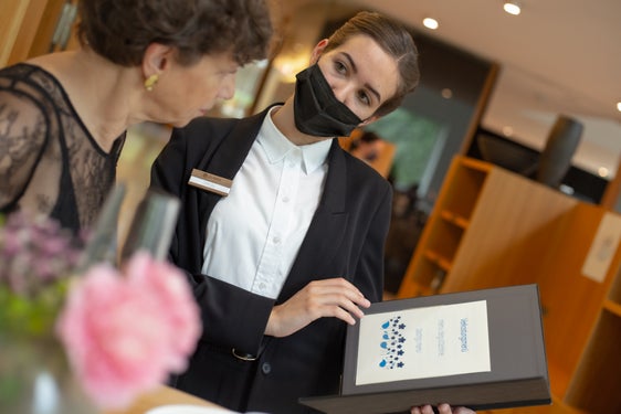 Direktorin Beatrix Kerschbaumer (l.) mit einer von sieben Kandidatinnen und Kandidaten, die ihr Können im Bereich Service vor den Augen der Prüfungskommission und den geladenen Gästen zeigte. (Foto: LPA/Landesberufsschule Savoy)