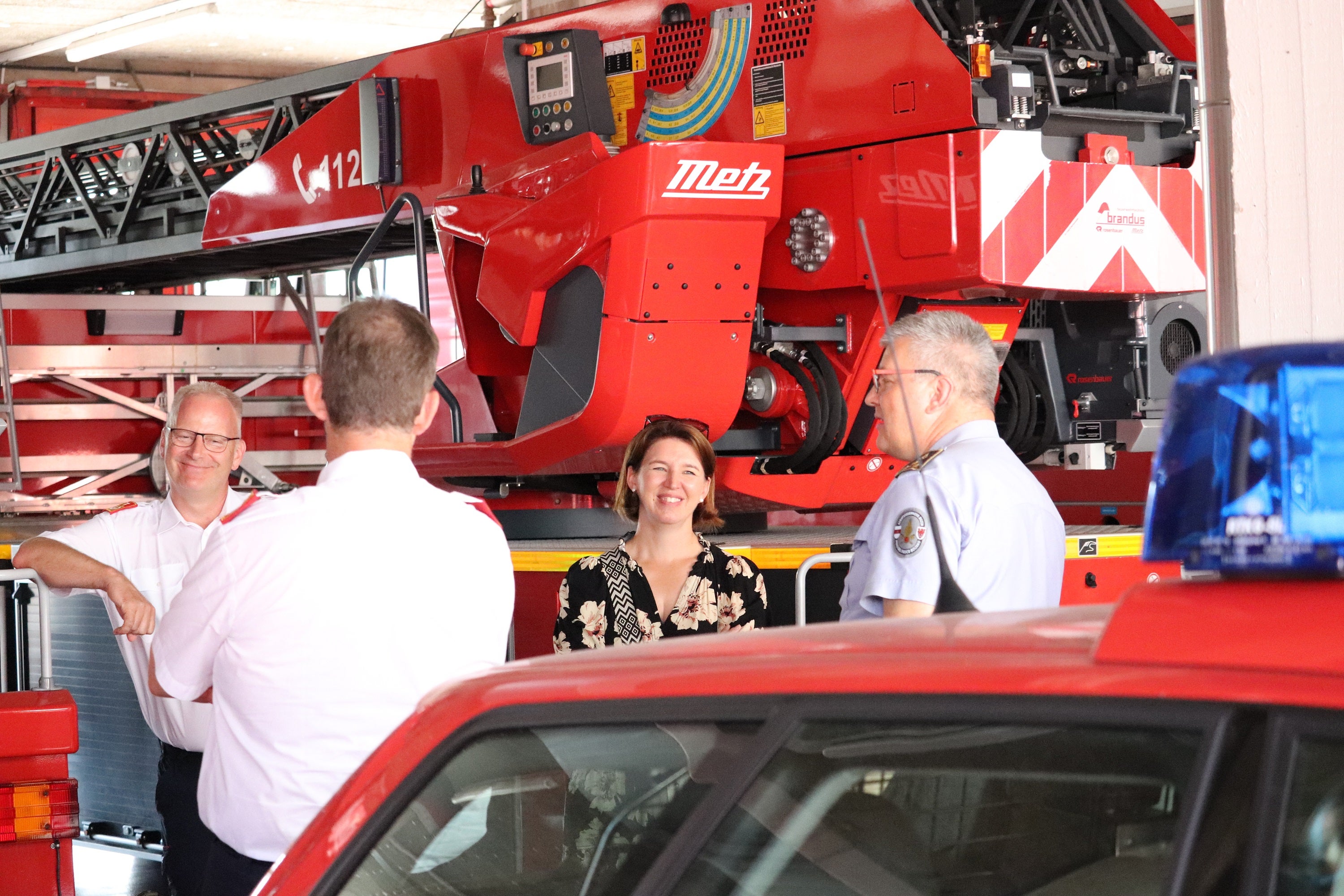 Die Landesrätin für Feuerwehren und Katastrophenschutz der oberösterreichischen Regionen mit dem oberösterreichischen Landesfeuerwehrkommandanten und seinem Stellvertreter in der Fahrzeughalle der Berufsfeuerwehr mit Berufsfeuerwehrkommandant Florian Alber (ganz rechts) (Foto: LPA/Maja Clara)