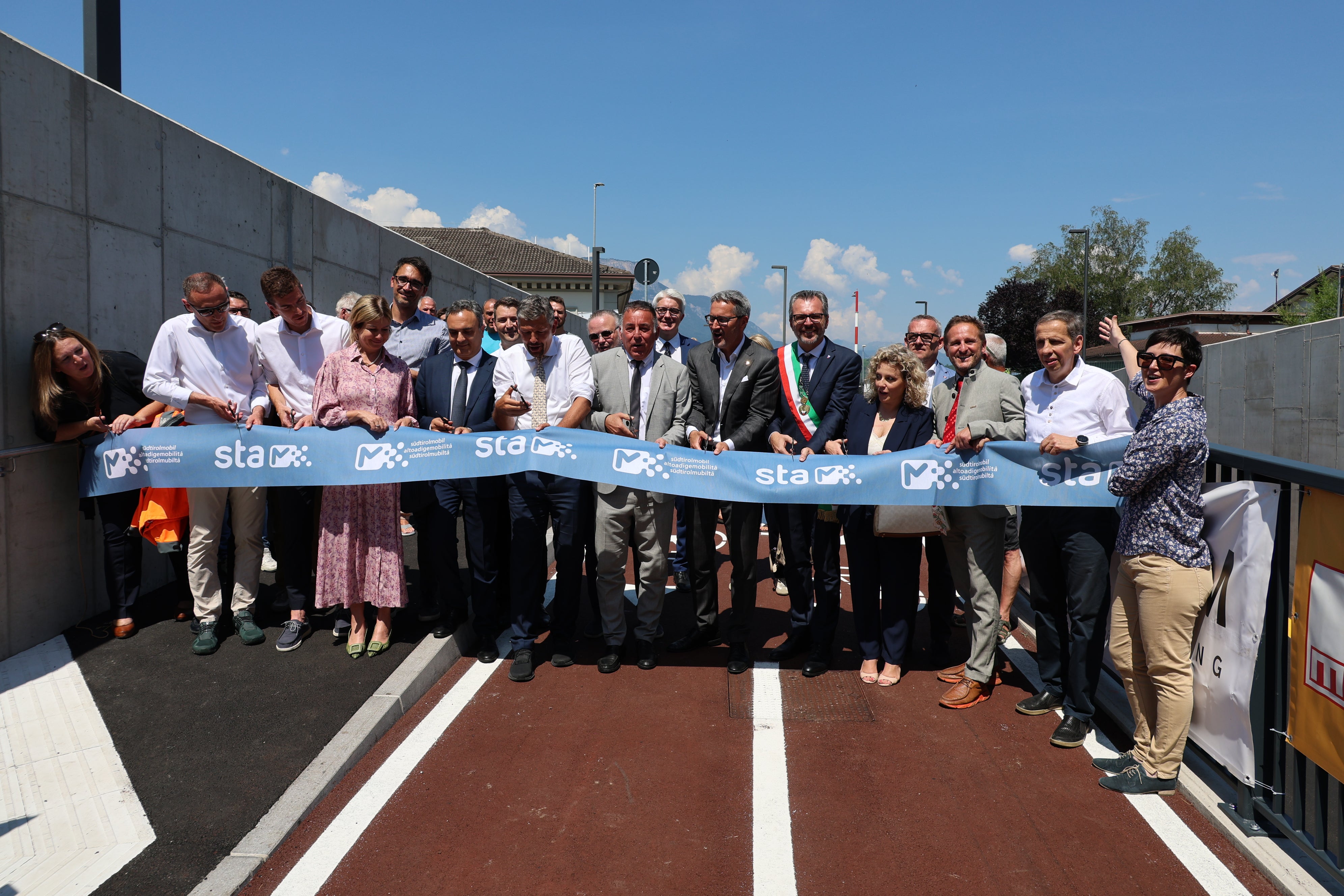 Die neue Unterführung in St. Jakob verbindet Leifers und Bozen direkt mit dem Flughafen und der Industriezone. Radfahrende, Fußgängerinnen und Fußgänger sowie Bussen können in der Unterführung sicher unterwegs sein. Zudem gilt die Unterführung als wichtiger Knotenpunkt für nachhaltige Mobilität. Im Bild der Banddurchschnitt bei der Eröffnung der Infrastruktur. (Foto: LPA/Ingo Dejaco)