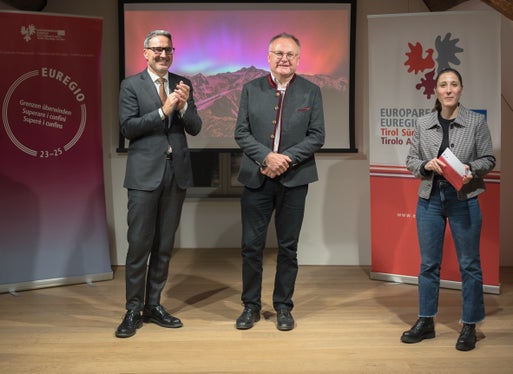 La cungratulazions per Hans Bergmann, tamez, che à fat la fotografia dancà dl calënder, ti ie unides fates dal presidënt dla Euregio y presidënt dla Jonta provinziela de Bulsan Arno Kompatscher, a man ciancia, y dala respunsabla dl pruiet Silvia Ramoser, a man drëta. (Foto: USP/Patrizia Corriero)