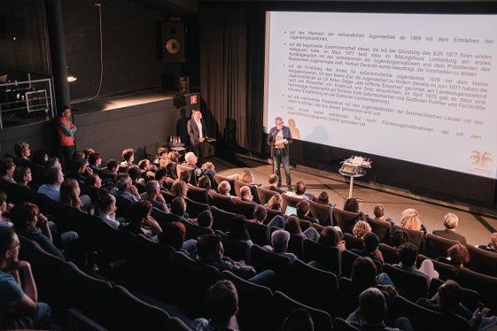 Konrad Pamer, Direktor des Amtes für Jugendarbeit, und Klaus Nothdurfter, ehemaliger Direktor des Amtes für Jugendarbeit im gut gefüllten Kinosaal des Filmclubs Bozen anlässlich der Veranstaltung 40 Jahre Landesgesetz zur Förderung der Jugendarbeit. (Foto: Philip Unterholzner/netz Offene Jugendarbeit)