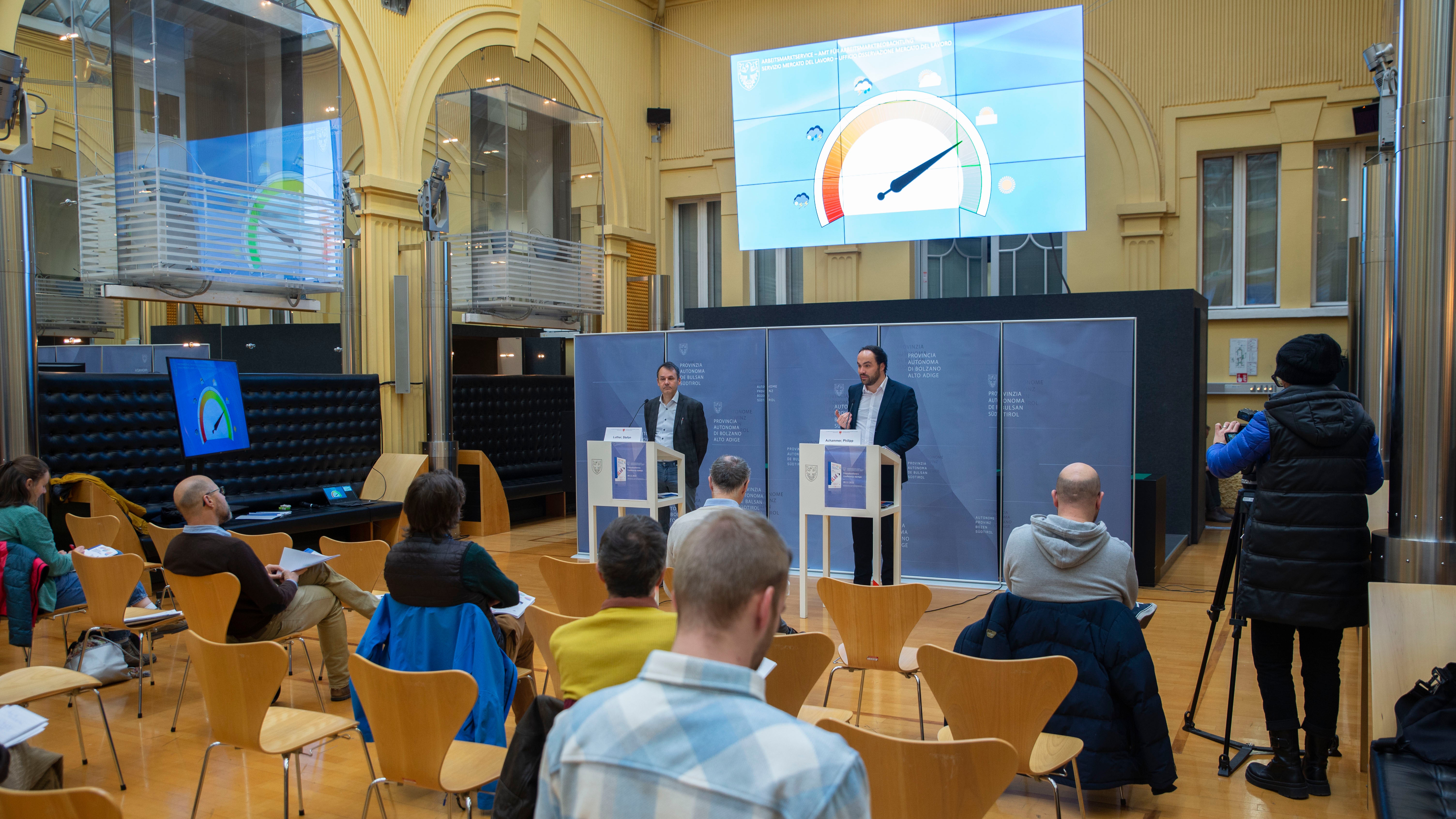 Die Arbeitsmarktbericht-Vorstellung mit Landesrat Philipp Achammer (am Podium r.) und Abteilungsdirektor Stefan Luther: Derzeit zeigt das Barometer fast vollen Sonnenschein an. (Foto: LPA/Fabio Brucculeri)