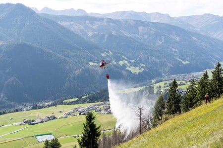 Collaborazione transfrontaliera durante l'esercitazione antincendio boschivo dell'Euregio: l'elicottero trentino scarica con precisione l'acqua sul terreno di esercitazione nel Tirolo Orientale. (Foto: Vigili del fuoco di Anras/Simon Kofler)

