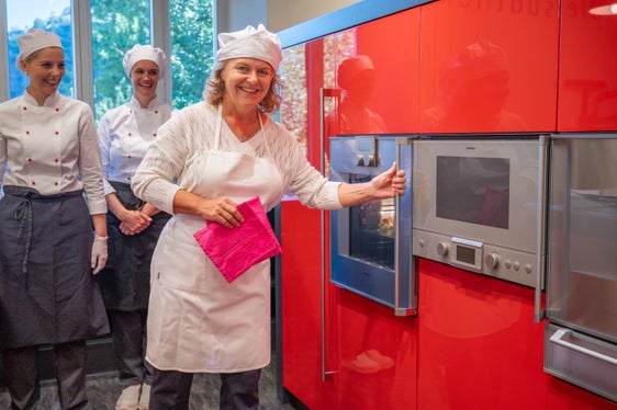 Landesrätin Pamer kam die Aufgabe zu, den während der Vorstellung von den Fachleherinnen Martina Gögele und Julia Dariz zubereiteten Scheiterhaufen aus dem Ofen zu holen. (Foto: LPA/Greta Stuefer)