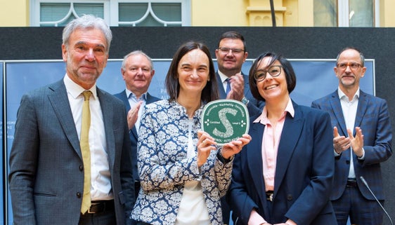 La destinazione Val d'Ega ha ottenuto il massimo livello di sostenibilità. La direttrice Verena Festi (con l'etichetta in mano) e Brigitte Zelger, componente del CdA  di Val d'Ega Turismo Soc. Coop.  (accanto a lei sulla destra) hanno ricevuto la certificazione dall'assessore provinciale Arnold Schuler (a sinistra) durante la conferenza stampa. Presenti anche il presidente di HGV Manfred Pinzger (in ultima fila, all'estrema sinistra), il presidente di IDM Hansi Pichler (in fondo, al centro) e il direttore di IDM Erwin Hinteregger (Foto: ASP/Fabio Brucculeri)