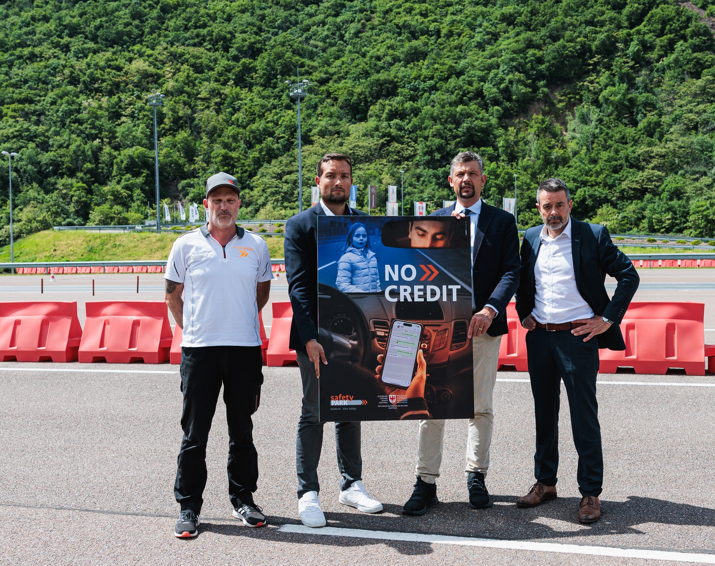 Ablenkungen im Straßenverkehr im Fokus: Safety-Park-Instructor Georg Huber, Safety-Park-Chef Lukas Nothdurfter, Mobilitätslandesrat Daniel Alfreider und STA-Direktor Joachim Dejaco mit dem Plakat zur heurigen Ausgabe der Kampagne No Credit für sicheres Fahren. (Foto: LPA/Ivan Brentegani)