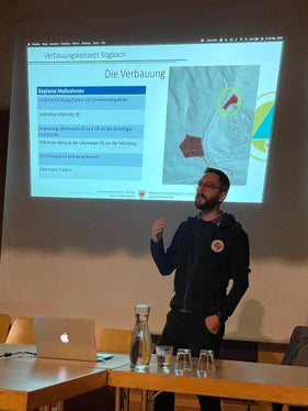 Techniker Jan Kobald stellte das Verbauungskonzeptes vor: Um ein Ausufern des Kogbachs im Mündungsbereich zu verhindern, müsste die Fläche eines dort stehenden Wohnhauses als Ausschotterungsfläche genutzt und mit einer rund 55 Meter langen Mauer umgrenzt werden. (Foto: LPA/Landesamt für Wildbach- und Lawinenverbauung Nord)