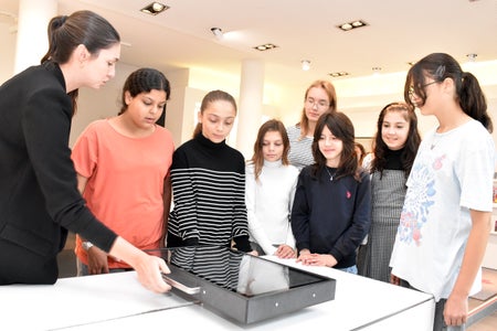 Zeitreisen durch Themen und Projekte der Euregio: Mitarbeiterin Sarah Müller (l.) erklärt Schülerinnen den digitalen „Schlitten“ der Euregio-Ausstellung in Innsbruck. (Foto: Land Tirol/Sidon)