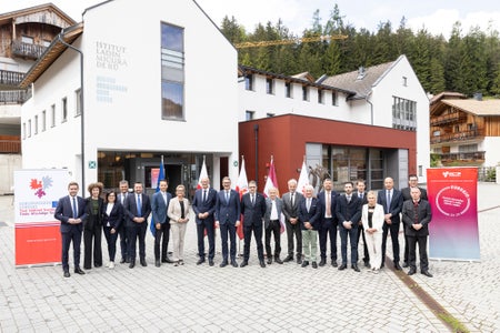 Foto di gruppo dell'Assemblea dell'Euregio con altri ospiti d'onore e dirigenti davanti all'Istitut ladin Micurà de Rü a San Martino in Val Badia: ulteriore rafforzamento delle agevolazioni per le famiglie con l'EuregioFamilyPass. (Foto: USP/Tiberio Sorvillo)