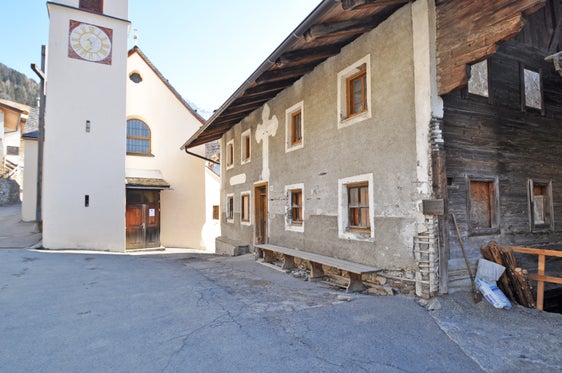 La frazione di Valtina con la chiesa di Sant'Antonio e il Wirtsguat: l'edificio a blocchi è visibile dall'esterno solo sulla facciata ovest. (Foto: Soprintendenza ai beni culturali) 