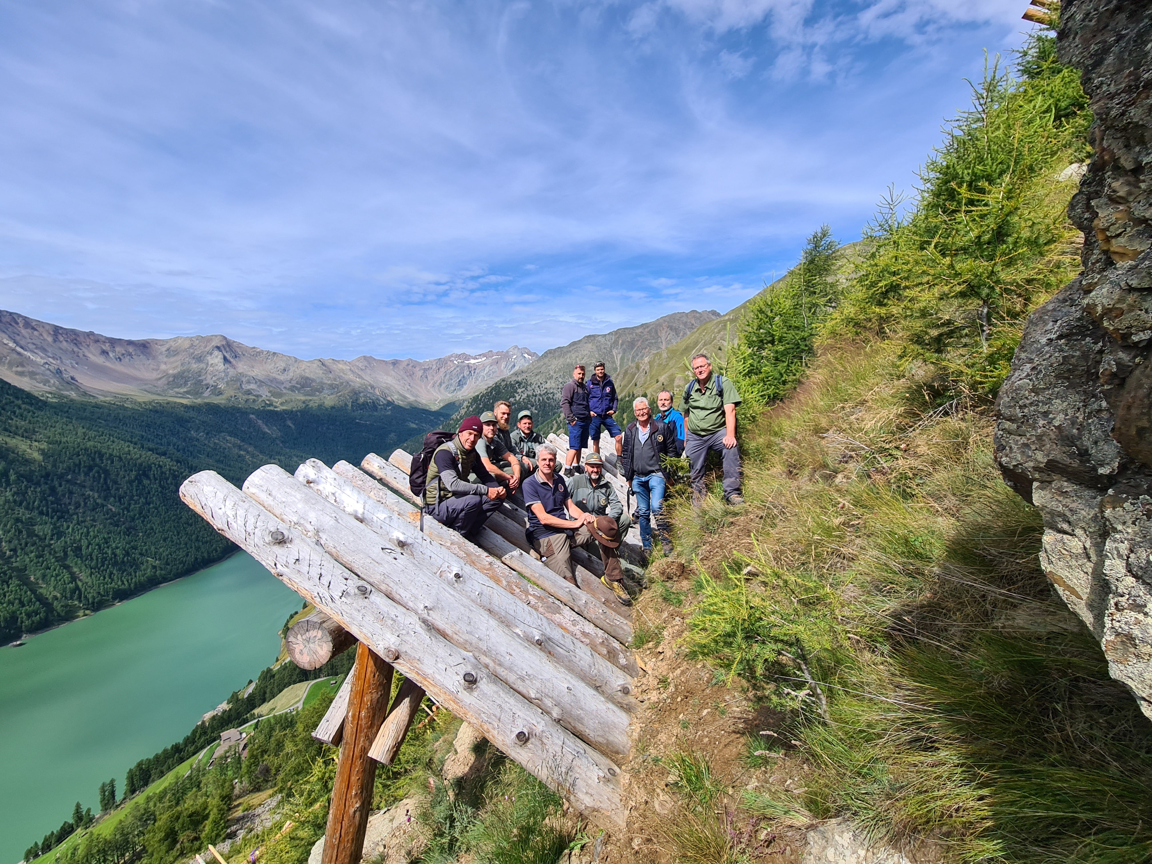 Foto di gruppo sulle strutture in legno di protezione dalle valanghe: gli operatori dell'Ufficio sistemazione bacini montani Ovest con i colleghi dell'Ispettorato forestale di Merano durante una visita al sistema di protezione delle valanghe Hochegg a Vernago in Val Senales (Foto: ASP/Ispettorato forestale di Merano)
