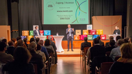 Il presidente della Provincia Arno Kompatscher (in mezzo), l'assessore Philipp Achammer (a sx) e la moderatrice Sabine Drescher (a dx) di fronte a 151 cittadine e cittadini durante la serata informativa (Foto: ASP)