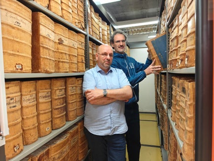 Gustav Pfeifer, direttore dell’Archivio provinciale (in primo piano nella foto), e il suo collaboratore Philipp Tolloi con i fondi storici dell’archivio. Oggi la maggior parte dei documenti digitali destinati a essere conservati a lungo termine viene archiviata digitalmente tramite il servizio ParER. (Foto: USP/Ursula Pirchstaller)