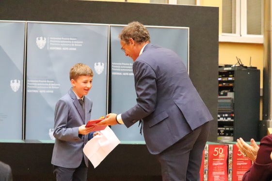 Gratulation und ein Geschenk für sein Gedicht über das Ladinische: Schulamtsleiter Heinrich Videsott und der Schüler Mattia der Mittelschule St. Ulrich. (Foto: LPA/Maja Clara)