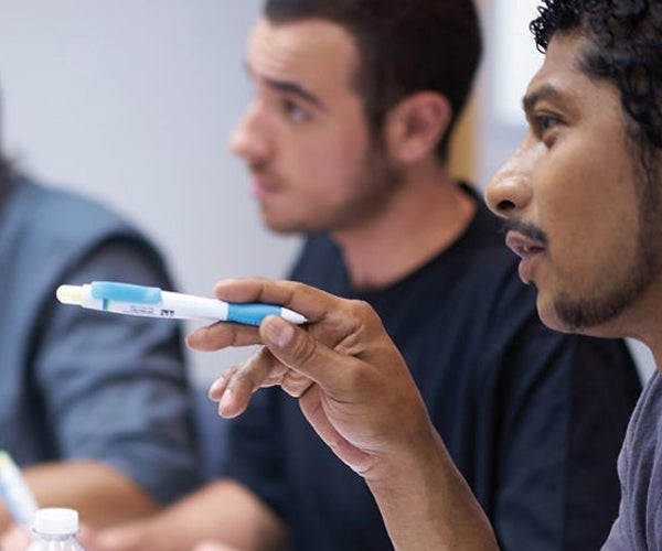 Man discussing in meeting whilst holding pen