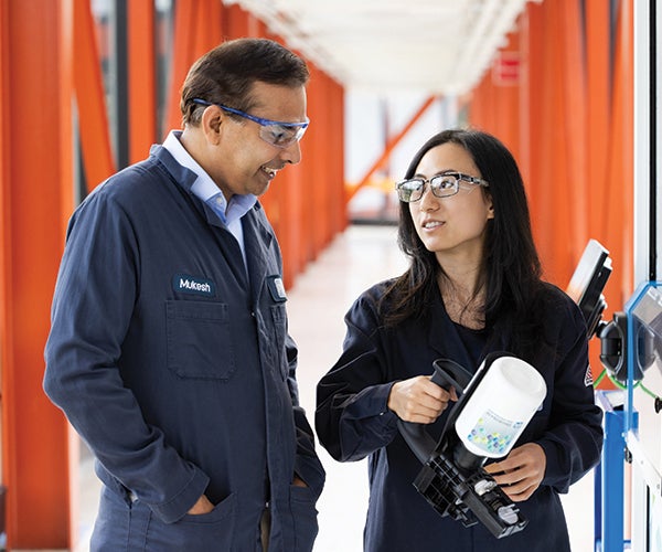 Male and female colleagues discussing information alongside machinery