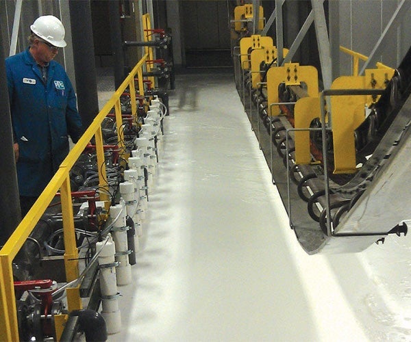 An electrocoat line moving over a bath or white liquid coating with yellow railings