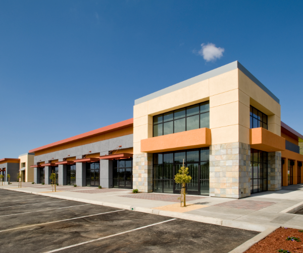 Large storefront painted in cream, grey and brown against an empty parking lot