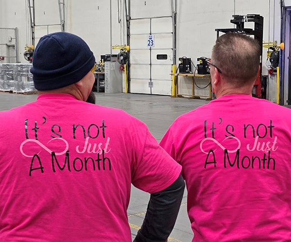 Two employees in factory wearing pink tshirts for Abilities First Network