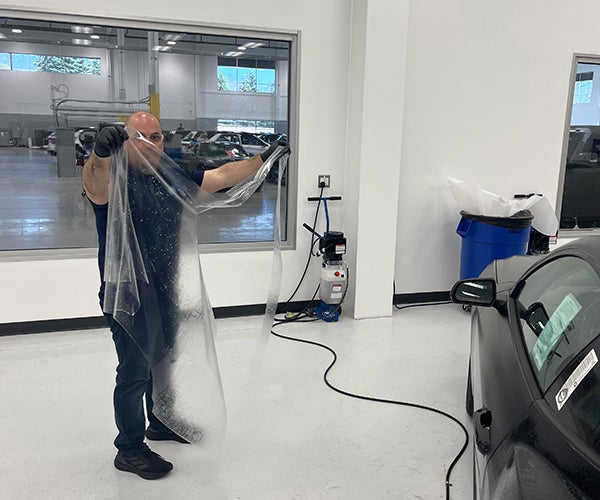 An auto body specialist holding pre-cut film application