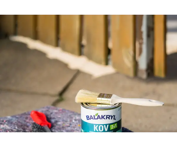Plechovka s barvou a štětec položené na modré plechovce