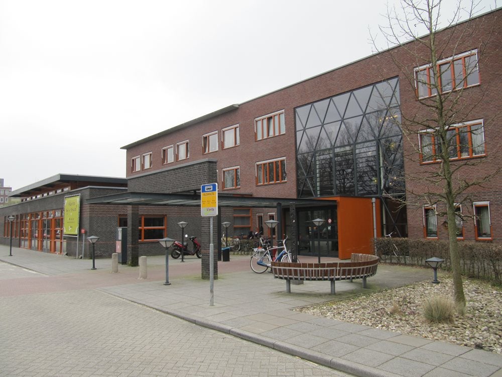 Een gebouw met een bankje en fietsen ervoor