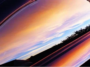 De weerspiegeling van een zonsondergang in een autospiegel.