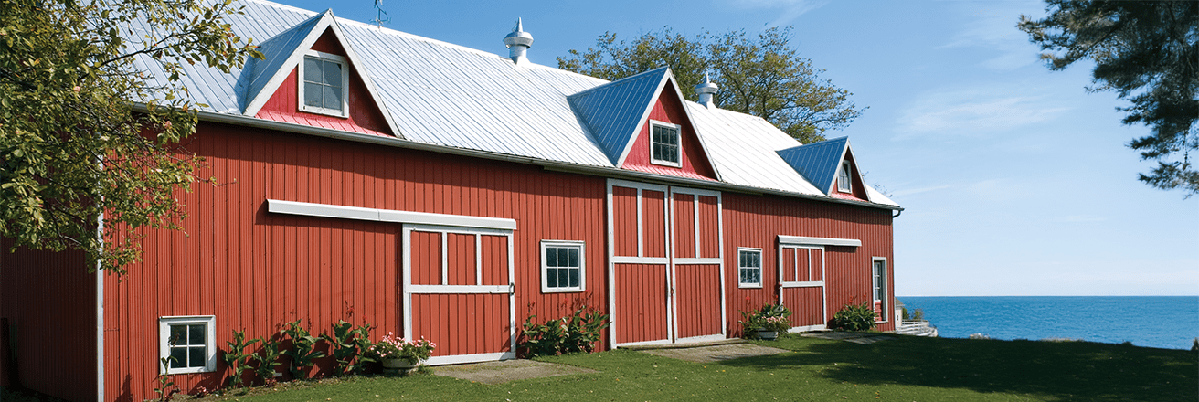 Red coil building with a white roof against blue water and sky