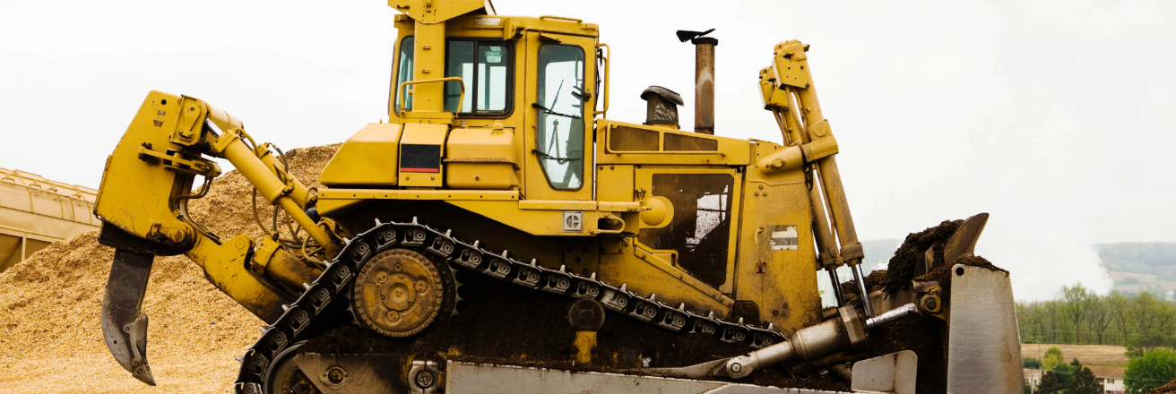 Yellow bulldozer in a quarry environment with piles of sand in the background