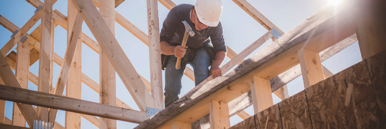 Man in white hard hat hammering lumber