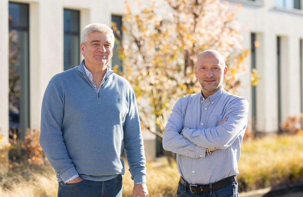 Twee mannen staan buiten met hun armen over elkaar